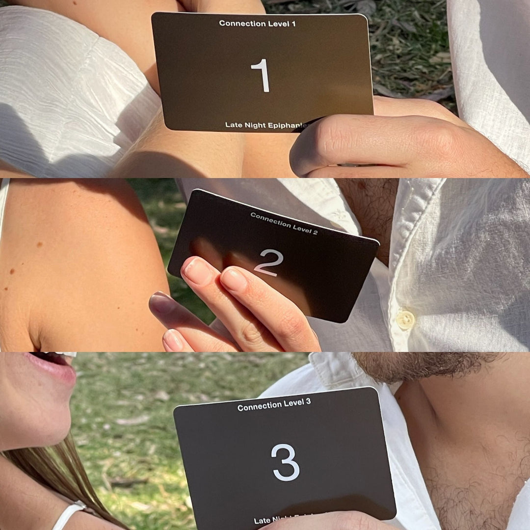 People holding Level 1, 2, and 3 cards from the Late Night Epiphanies card game during a picnic.