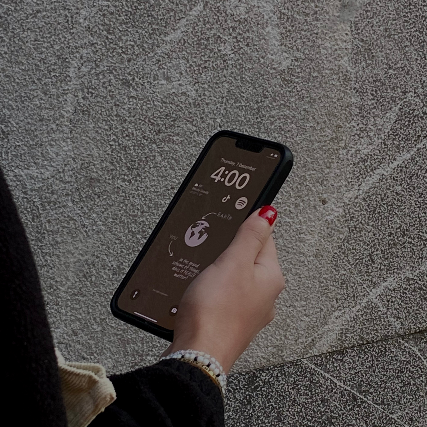 Image of someone holding a phone with a brown LNE wallpaper that says "in the grand scheme of things, does it REALLY matter?"