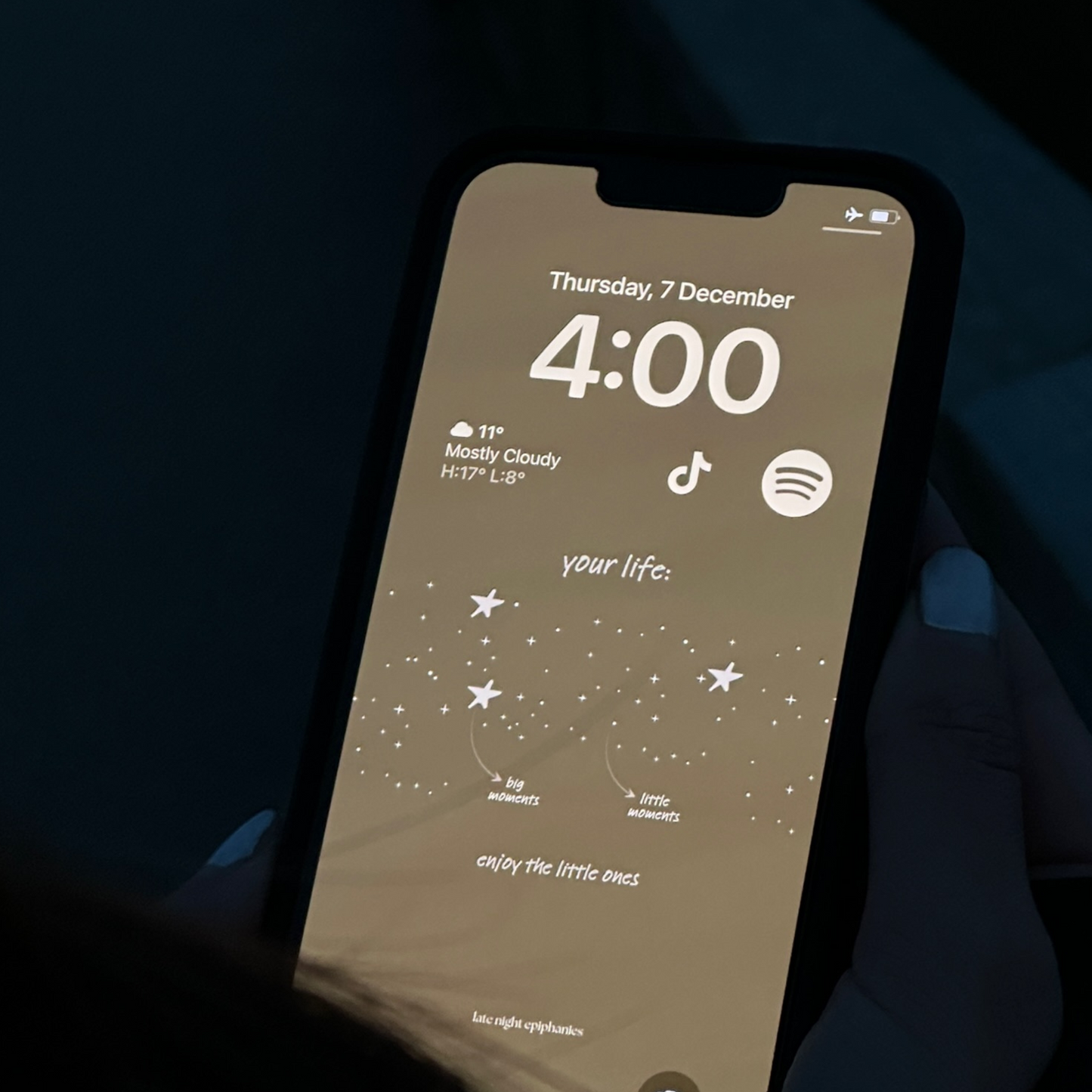 Image of an iPhone with a Late Night Epiphanies wallpaper that says "your life:" and is followed by an illustration of a sky full of stars, with a bunch of little starts and 4 bigger stars. 2 arrows point to the stars, one points to the big star and says "big moments" and another points to a big star and says "big moments." At the bottom it says "enjoy the little ones". 